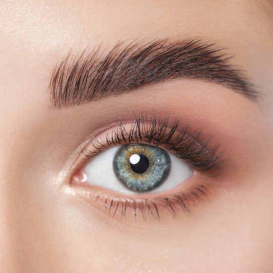 Beautiful woman with long eyelashes, beautiful make-up and thick eyebrows. Beautiful blue eyes close up. Looking at the camera. Cosmetology concept